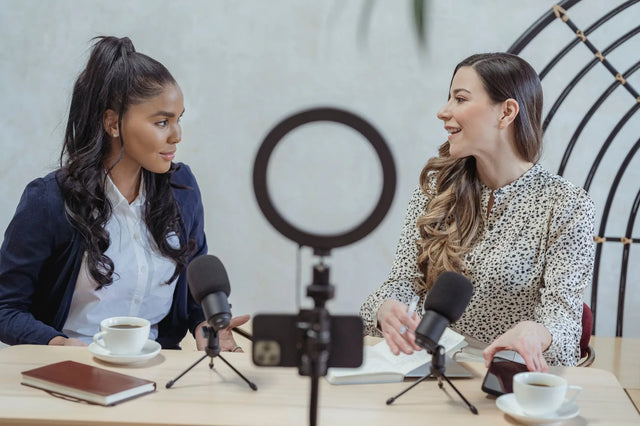 Two people recording an interview with microphones and a ring light